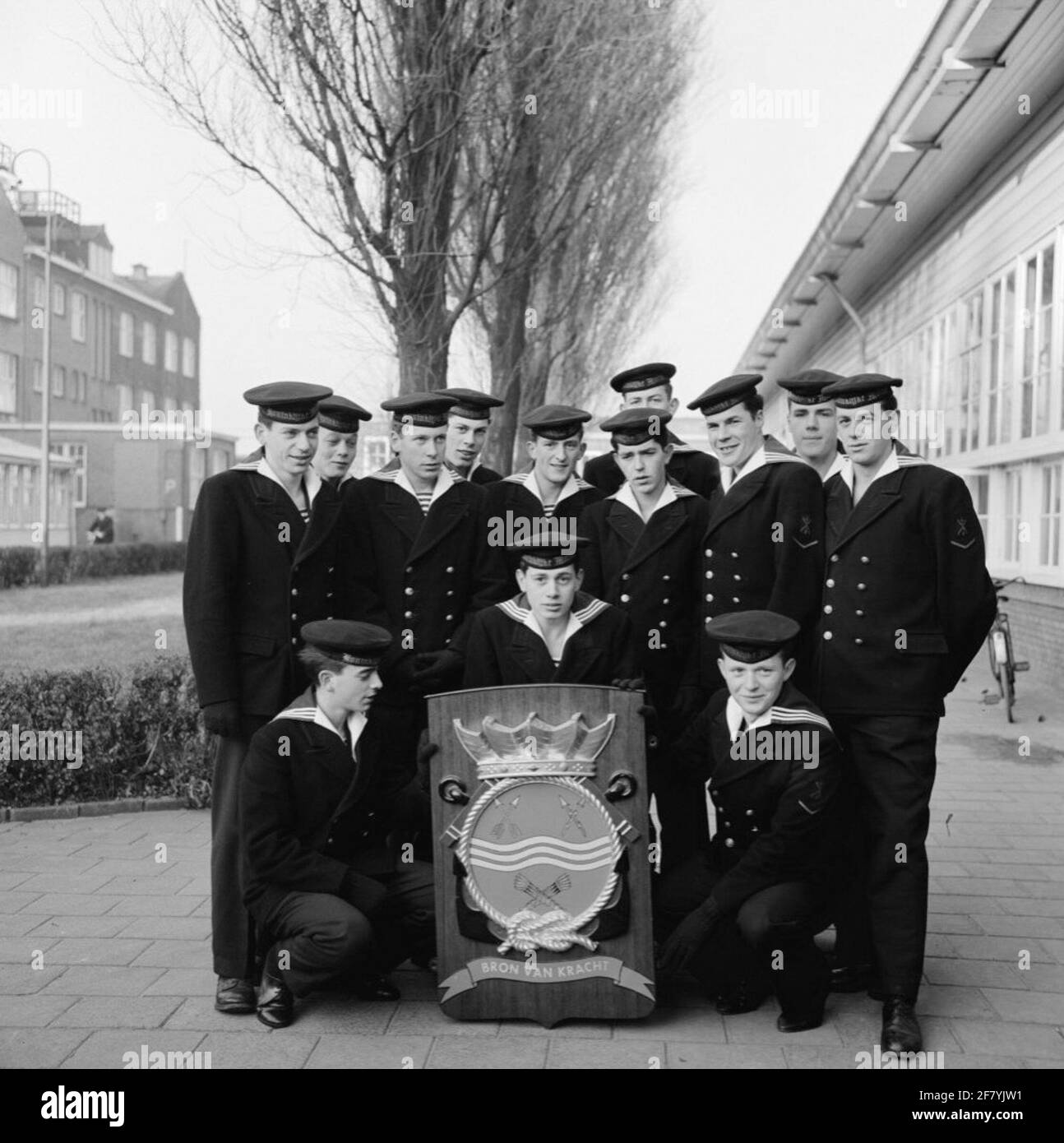 Foto di classe realizzata sul sito delle caserme marine di Amsterdam (MKAD) presso i corsi tecnici della Royal Netherlands Marine (Toka). Una classe con ingegneri elettrici della 2° classe (Elmnt 2) si pone con lo stemma del Tkm. Foto Stock
