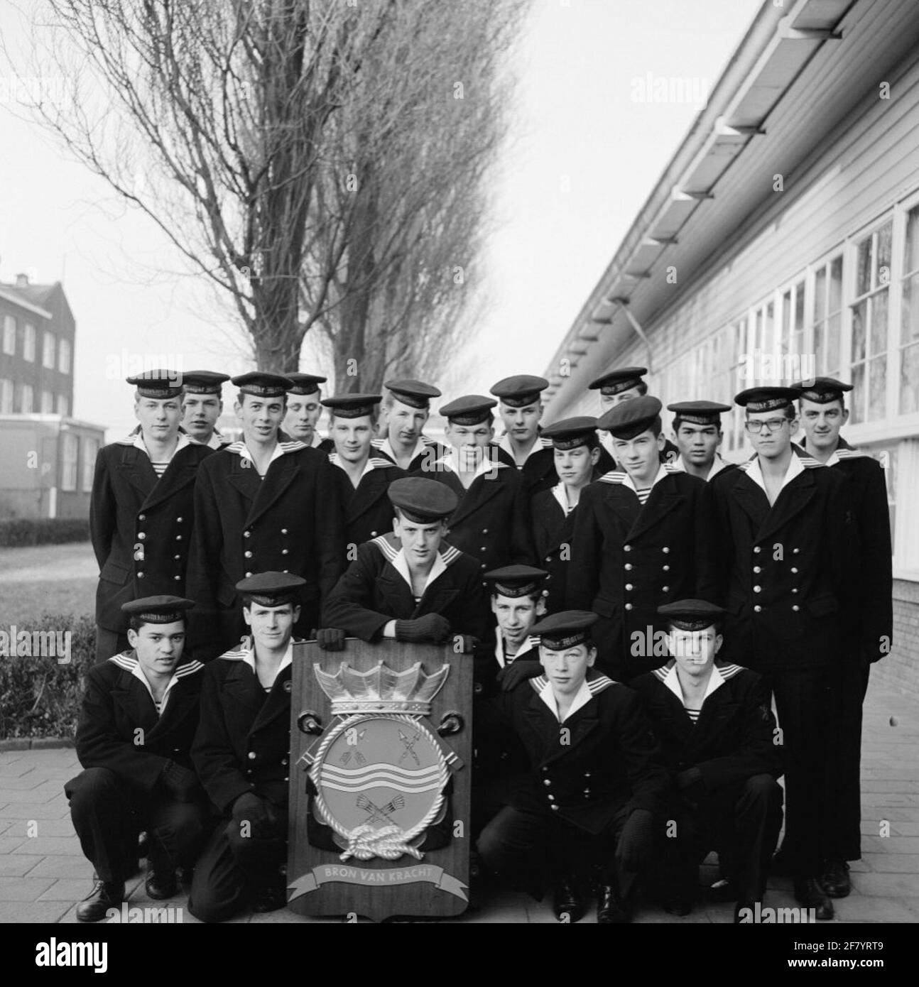 Foto di classe realizzata sul sito delle caserme marine di Amsterdam (MKAD) presso i corsi tecnici della Royal Netherlands Marine (Toka). Una classe con elettricisti della 3° classe (Elmnt 3) si pone con lo stemma del Tkm. Foto Stock