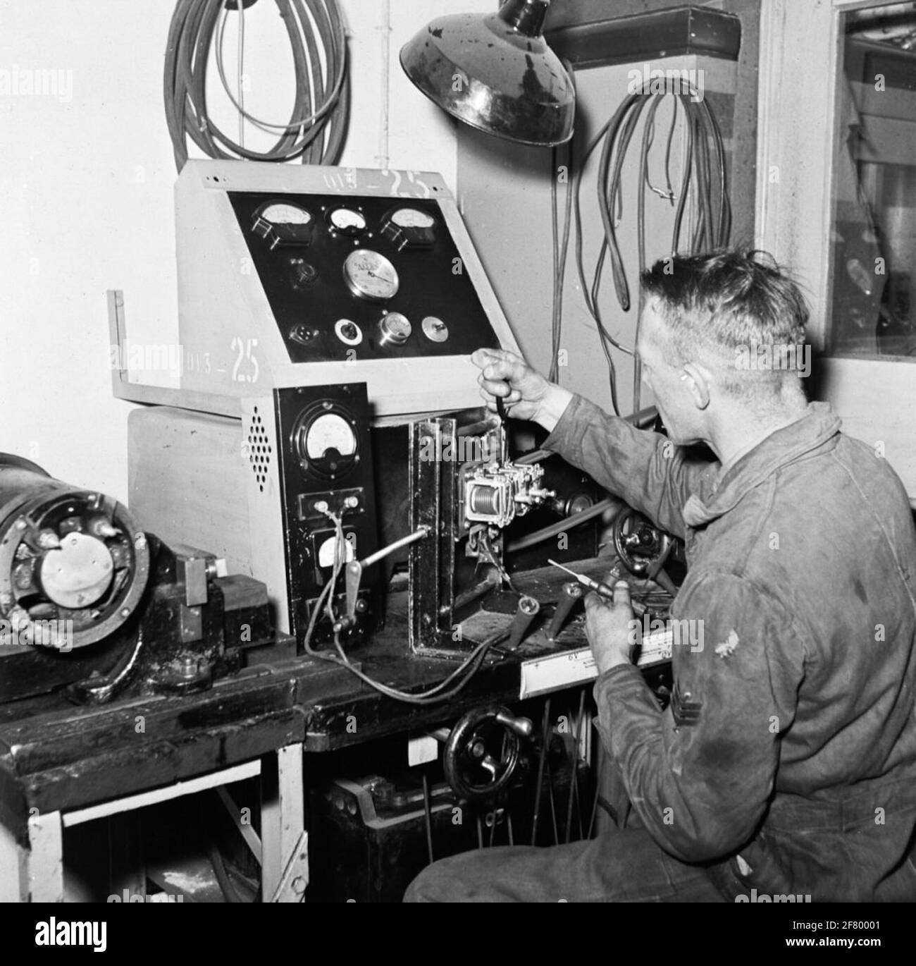 Posto di lavoro Electra automatico con banco di prova Allen di tipo vecchio. Il meccanico è collegato alla regolazione di un regolatore di tensione. Foto Stock