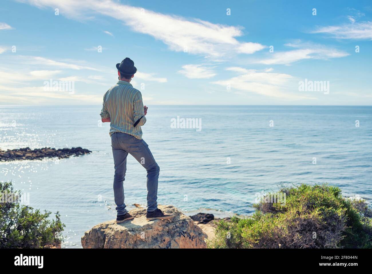 Un giovane hipster avventuroso osserva l'orizzonte in un turista zona spiaggia Foto Stock