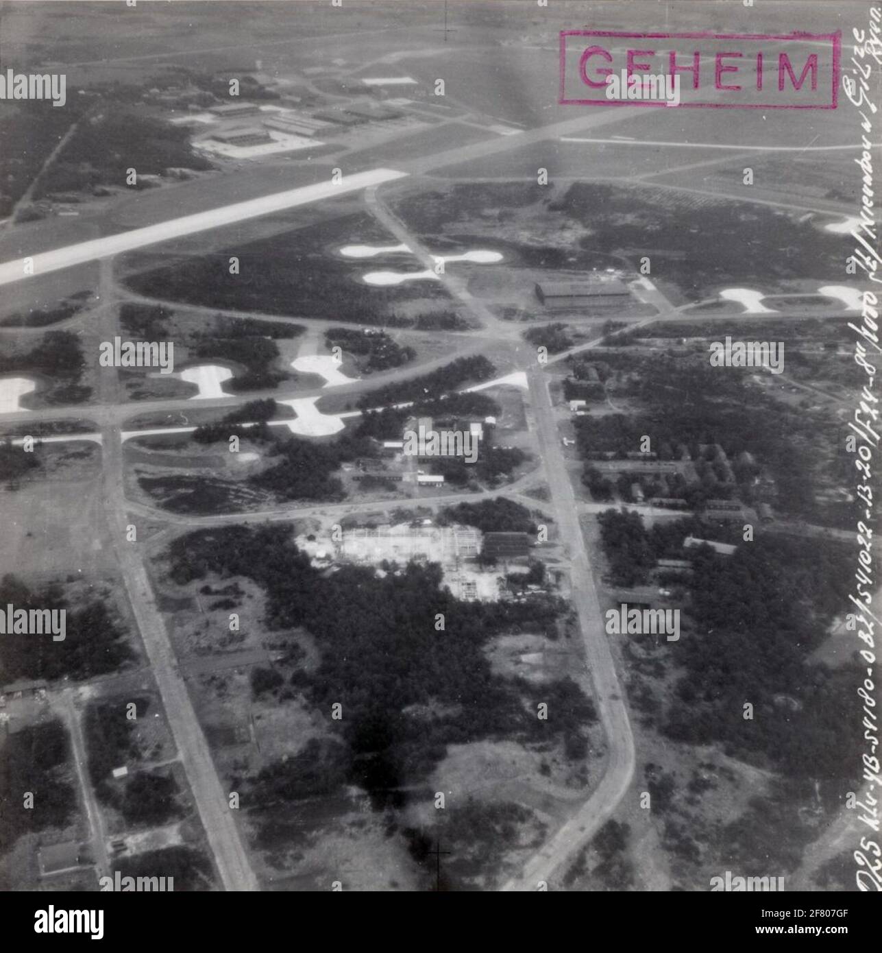 Al centro della foto c'è la costruzione B 209 del DVM. In questo edificio sono ospitate in seguito le lamiere, i lavori bancari, i sistemi e le officine idrauliche. L'alleanza è hangar 409. Un aereo da lezione è parcheggiato sull'altro lato della strada. Oltre a questo hangar, gli edifici del laboratorio di Falegnameria DVM, BE.240 + 238. Di fronte al 209 e al 409 si trova il Kort Kampstraat con O.A. Bureau Commander DVM, (249) Sala da pranzo (244) e ufficio aziendale (nato nel 248). In alto a sinistra ci sono una serie di appendiabiti e aerei di classe accanto al lavoro '10' (L) - '28' (R). Serie. Foto Stock