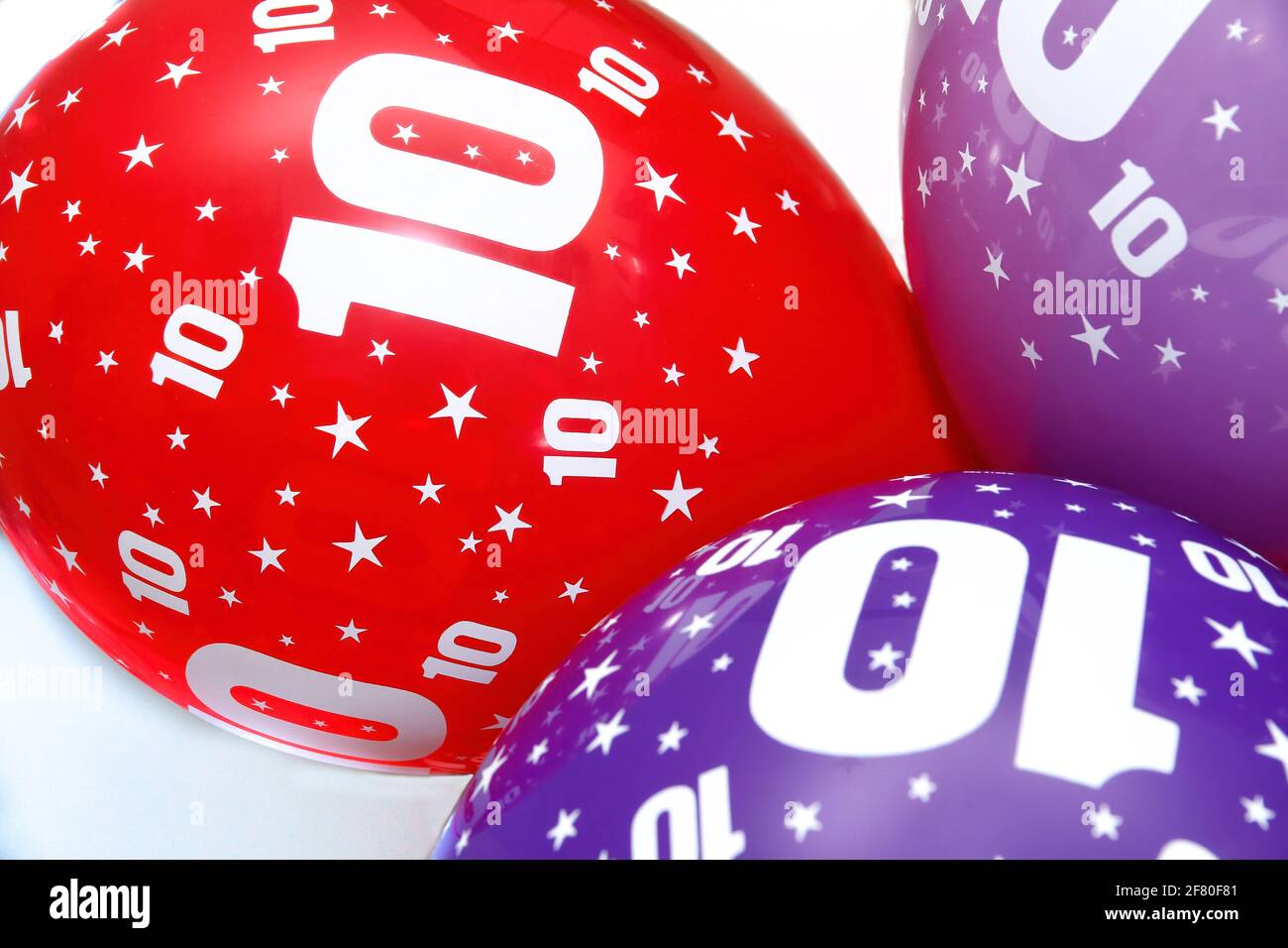 tre palloncini colorati con stelle e il numero 10, palloncini di compleanno, rosso blu e viola, festa del decimo anniversario, orizzontale Foto Stock