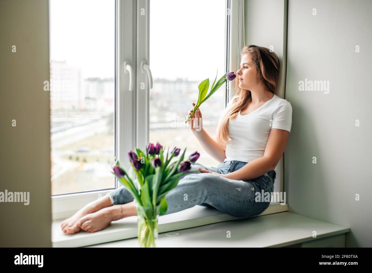 Amabile ragazza femminile nel fine settimana mattina. Bouquet di tulipani Foto Stock