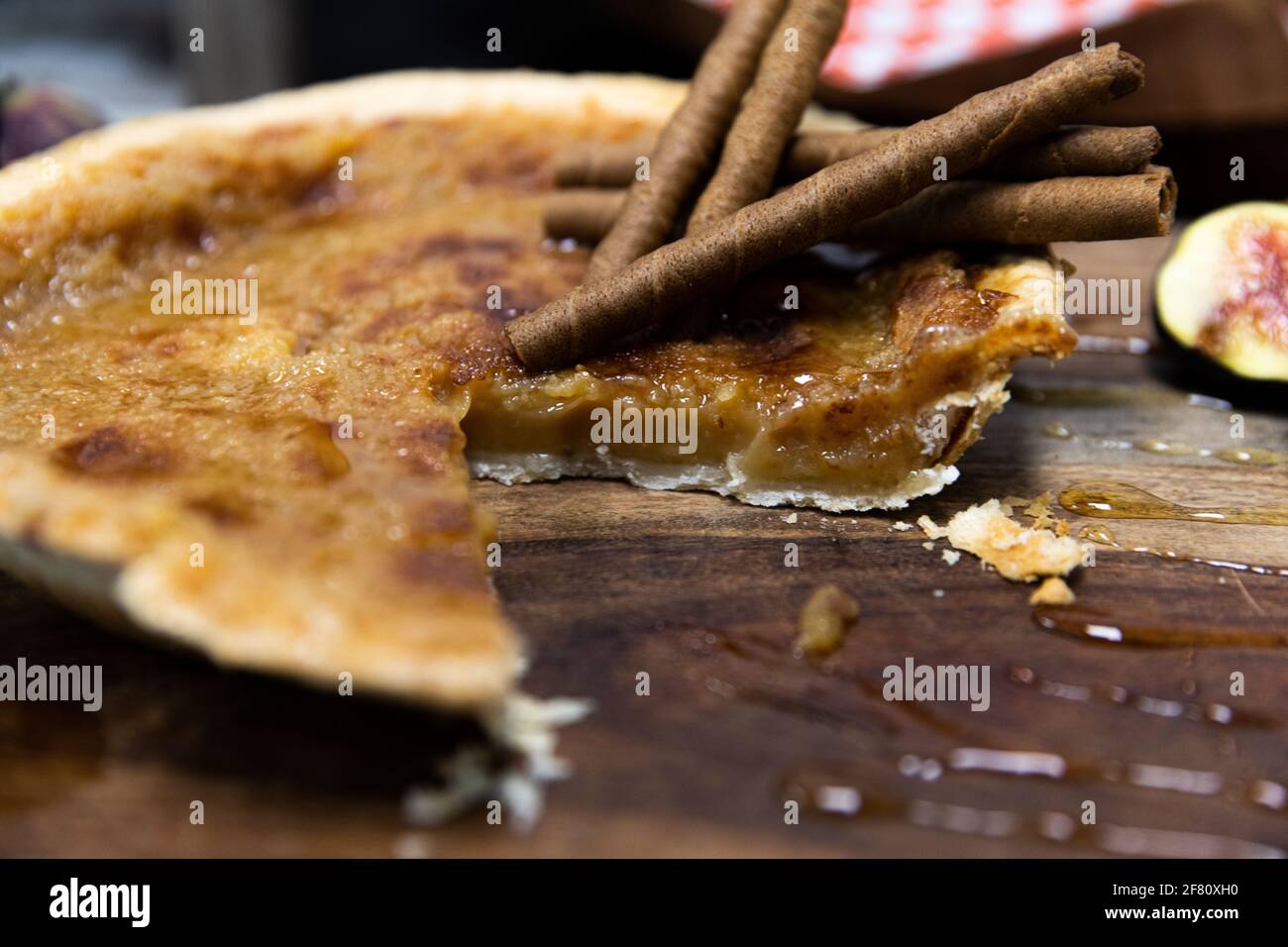 Torta di zucchero con bastoncini di cannella in cima con una fetta mancante su una tavola di legno Foto Stock