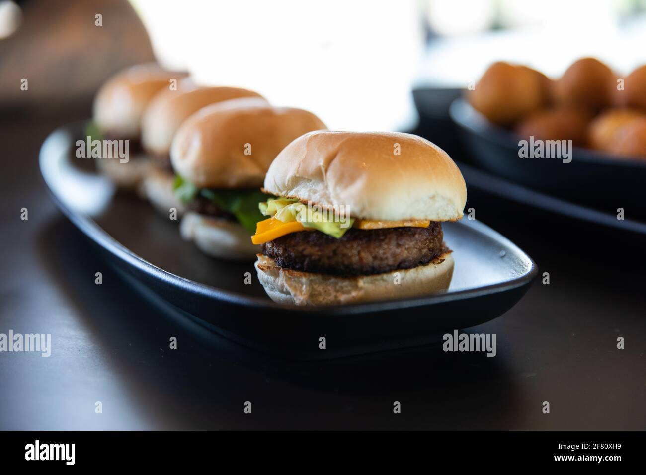 mini hamburger serviti su un lungo piatto nero Foto Stock