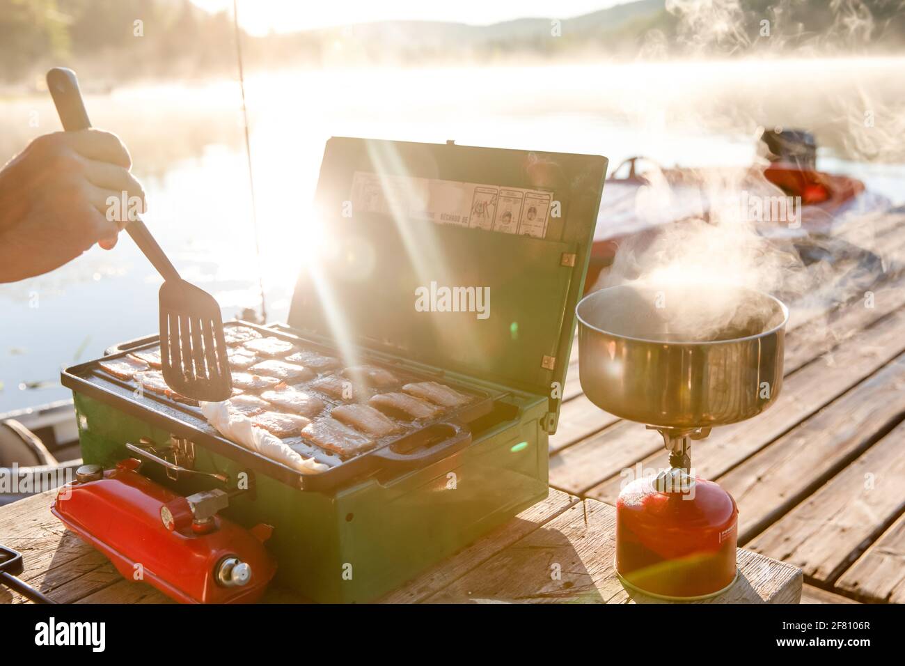 piccolo fornello verde portatile con pancetta e una pentola una seconda stufa a propano Foto Stock