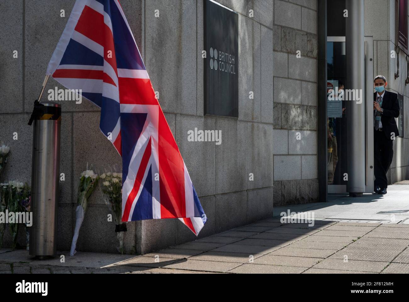 Hong Kong, Cina. 10 Apr 2021. Una guardia di sicurezza del British Council si trova all'ingresso mentre i lutto si riuniscono all'esterno dell'ambasciata del Consolato Generale britannico Hong Kong dopo l'annuncio della morte del Principe Filippo di Gran Bretagna a Hong Kong. Il principe Filippo, marito della regina Elisabetta II morì a 99 anni. (Foto di Miguel candela/SOPA Images/Sipa USA) Credit: Sipa USA/Alamy Live News Foto Stock