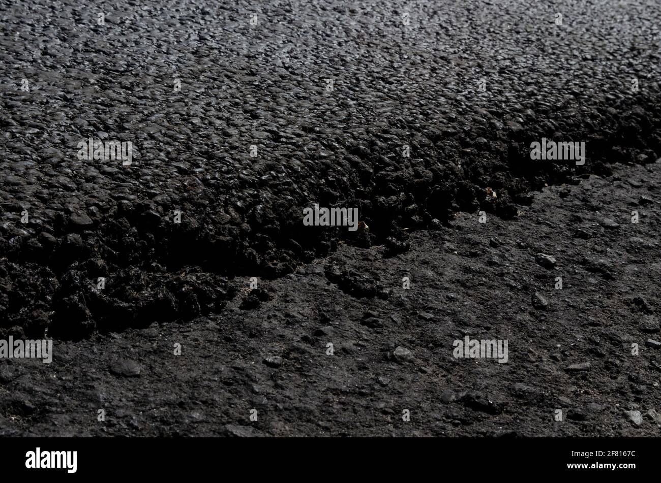 Due strati di asfalto, uno che copre l'altro. Tecnologie di riparazione stradale. Strada granulare grigio scuro, fondo stradale asfaltato vialetto. Arresto liquido Foto Stock