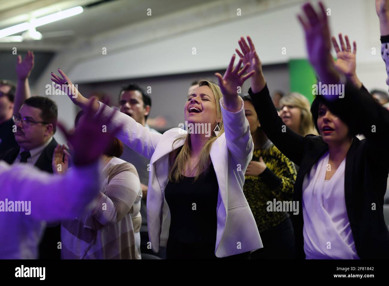 I praticanti della fede evangelica alzano le mani durante l'evento evangelico nella Comunità evangelica zona Sud di Londra, Regno Unito Foto Stock