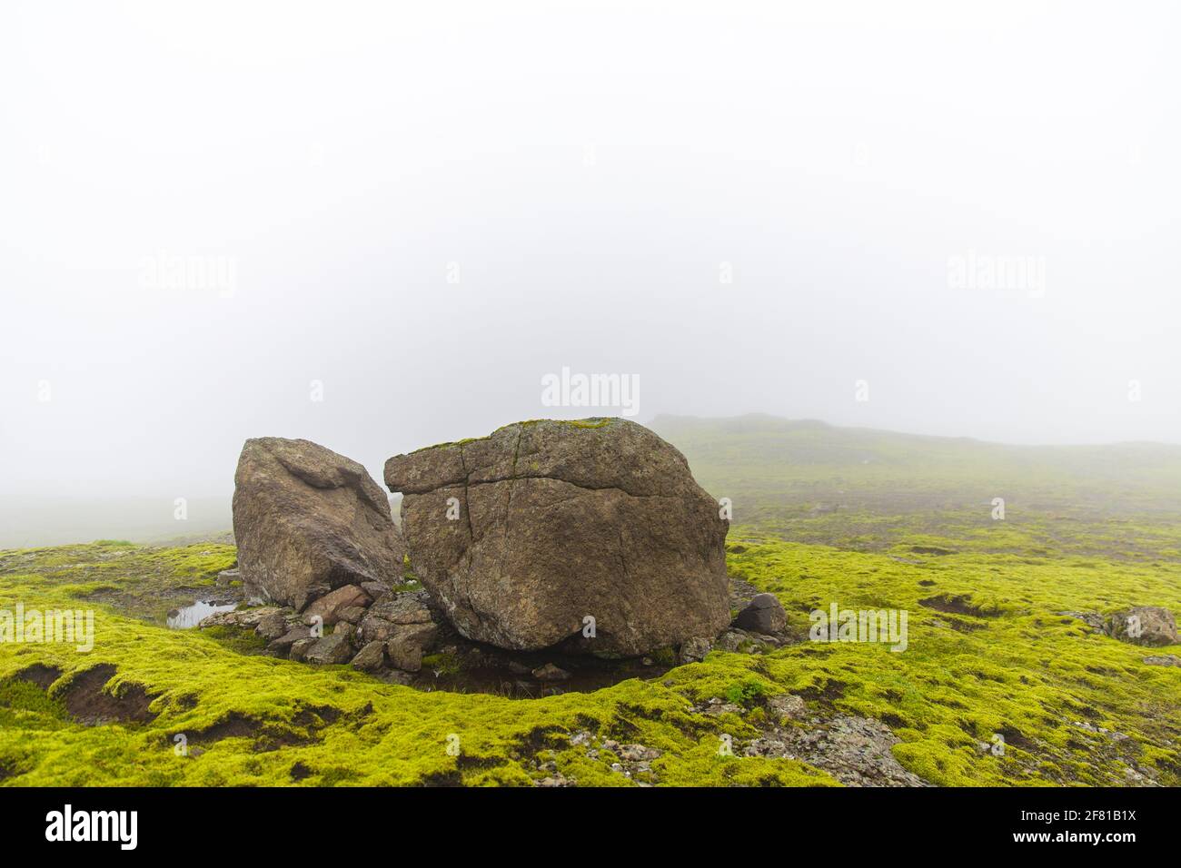 grande pietra nel mezzo di un campo di erba verde in un giorno molto foggy Foto Stock