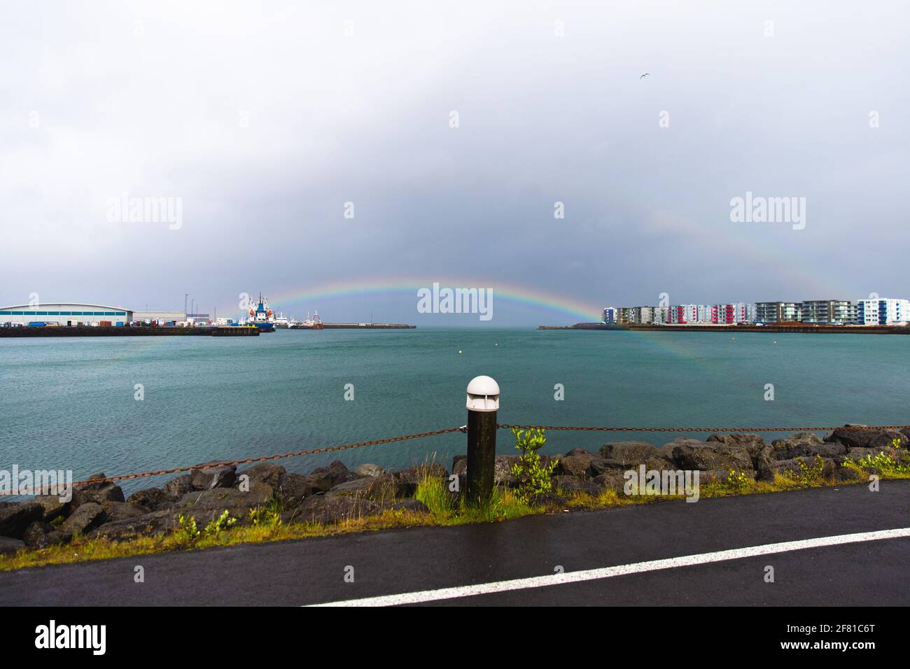 arcobaleno completo su un lago in una giornata molto nuvolosa accanto a una strada Foto Stock