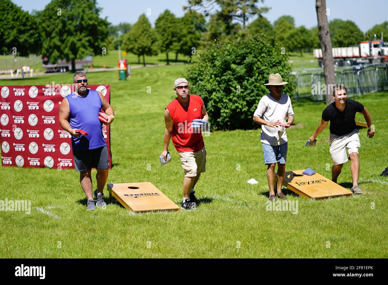 I maschi e le femmine giocano un gioco di lancio di sacco di fagioli all'evento del fine settimana di Walleye al parco del lago, come una comunità si riuniscono. Foto Stock I maschi e le femmine giocano un gioco di lancio di sacco di fagioli all'evento del fine settimana di Walleye al parco del lago, come una comunità si riuniscono. Foto Stock