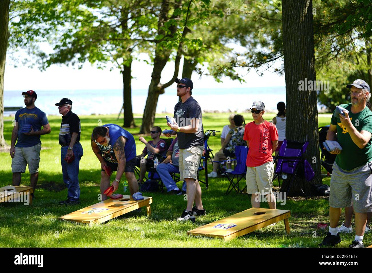 I maschi e le femmine giocano un gioco di lancio di sacco di fagioli all'evento del fine settimana di Walleye al parco del lago, come una comunità si riuniscono. Foto Stock I maschi e le femmine giocano un gioco di lancio di sacco di fagioli all'evento del fine settimana di Walleye al parco del lago, come una comunità si riuniscono. Foto Stock