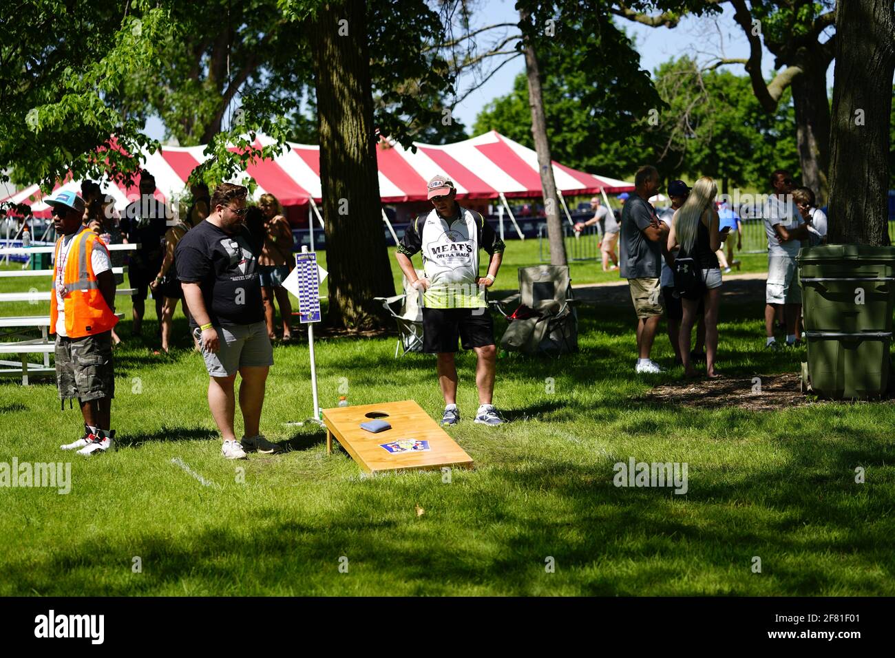 I maschi e le femmine giocano un gioco di lancio di sacco di fagioli all'evento del fine settimana di Walleye al parco del lago, come una comunità si riuniscono. Foto Stock I maschi e le femmine giocano un gioco di lancio di sacco di fagioli all'evento del fine settimana di Walleye al parco del lago, come una comunità si riuniscono. Foto Stock