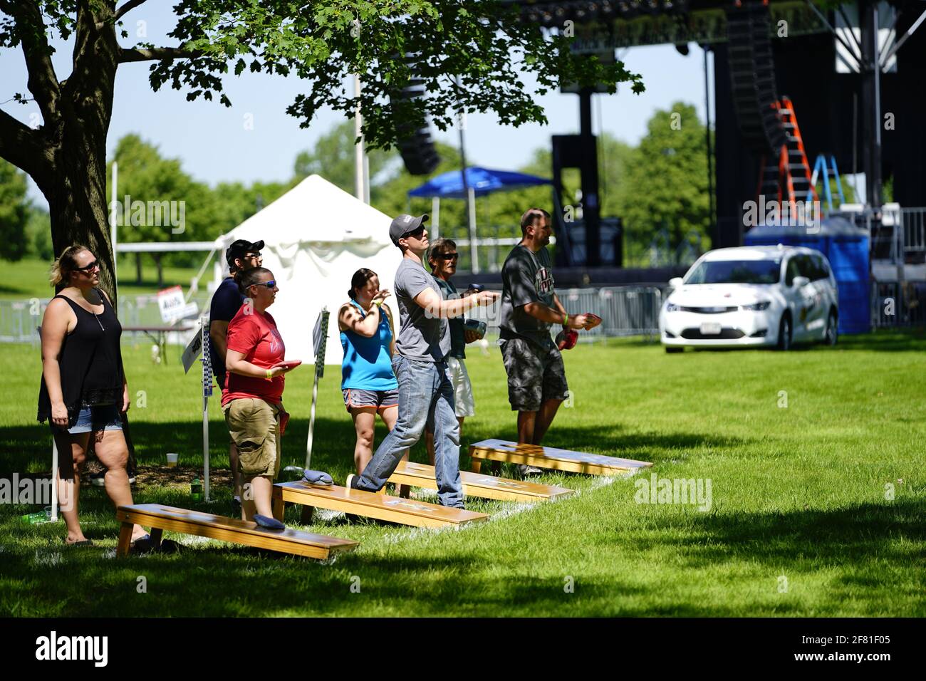 I maschi e le femmine giocano un gioco di lancio di sacco di fagioli all'evento del fine settimana di Walleye al parco del lago, come una comunità si riuniscono. Foto Stock I maschi e le femmine giocano un gioco di lancio di sacco di fagioli all'evento del fine settimana di Walleye al parco del lago, come una comunità si riuniscono. Foto Stock