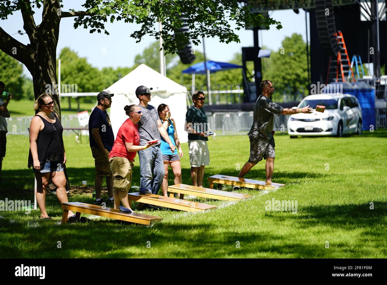 I maschi e le femmine giocano un gioco di lancio di sacco di fagioli all'evento del fine settimana di Walleye al parco del lago, come una comunità si riuniscono. Foto Stock I maschi e le femmine giocano un gioco di lancio di sacco di fagioli all'evento del fine settimana di Walleye al parco del lago, come una comunità si riuniscono. Foto Stock