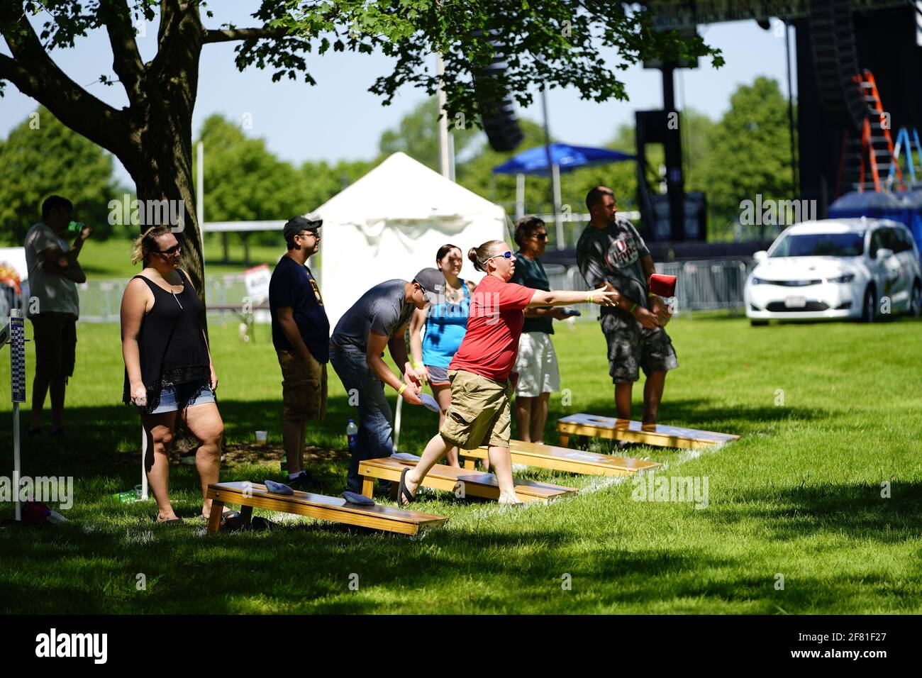 I maschi e le femmine giocano un gioco di lancio di sacco di fagioli all'evento del fine settimana di Walleye al parco del lago, come una comunità si riuniscono. Foto Stock I maschi e le femmine giocano un gioco di lancio di sacco di fagioli all'evento del fine settimana di Walleye al parco del lago, come una comunità si riuniscono. Foto Stock