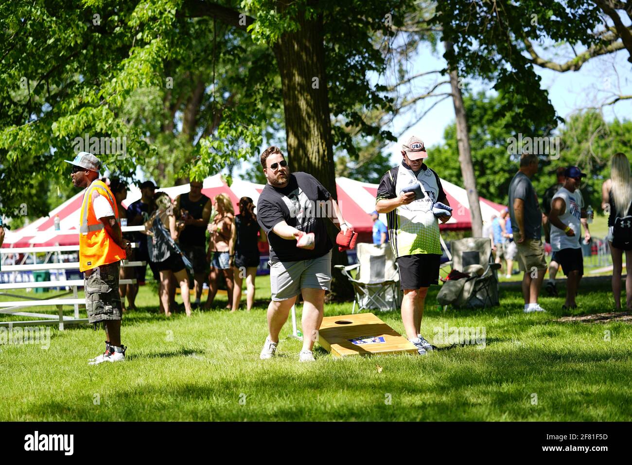 I maschi e le femmine giocano un gioco di lancio di sacco di fagioli all'evento del fine settimana di Walleye al parco del lago, come una comunità si riuniscono. Foto Stock I maschi e le femmine giocano un gioco di lancio di sacco di fagioli all'evento del fine settimana di Walleye al parco del lago, come una comunità si riuniscono. Foto Stock