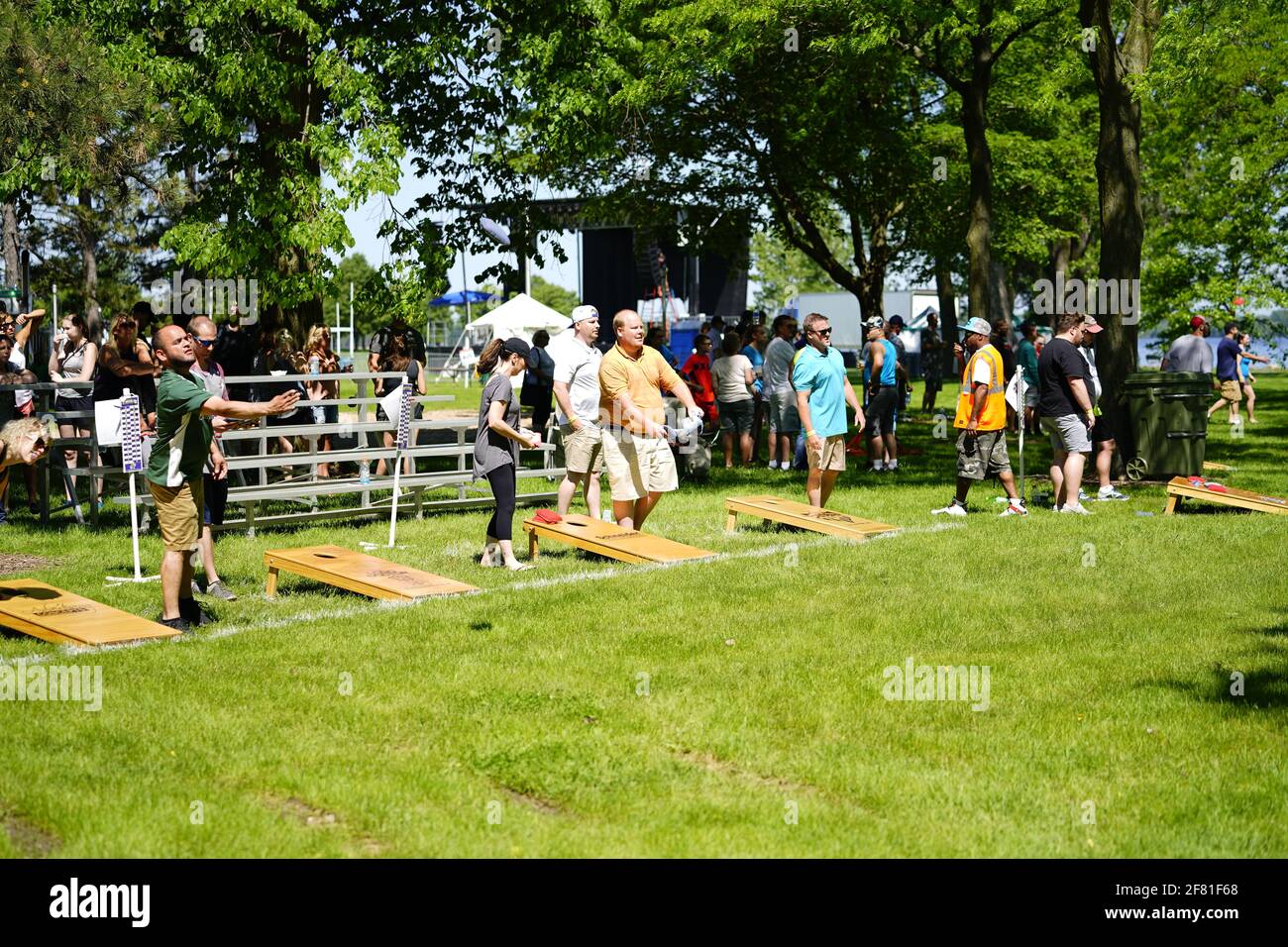 I maschi e le femmine giocano un gioco di lancio di sacco di fagioli all'evento del fine settimana di Walleye al parco del lago, come una comunità si riuniscono. Foto Stock I maschi e le femmine giocano un gioco di lancio di sacco di fagioli all'evento del fine settimana di Walleye al parco del lago, come una comunità si riuniscono. Foto Stock