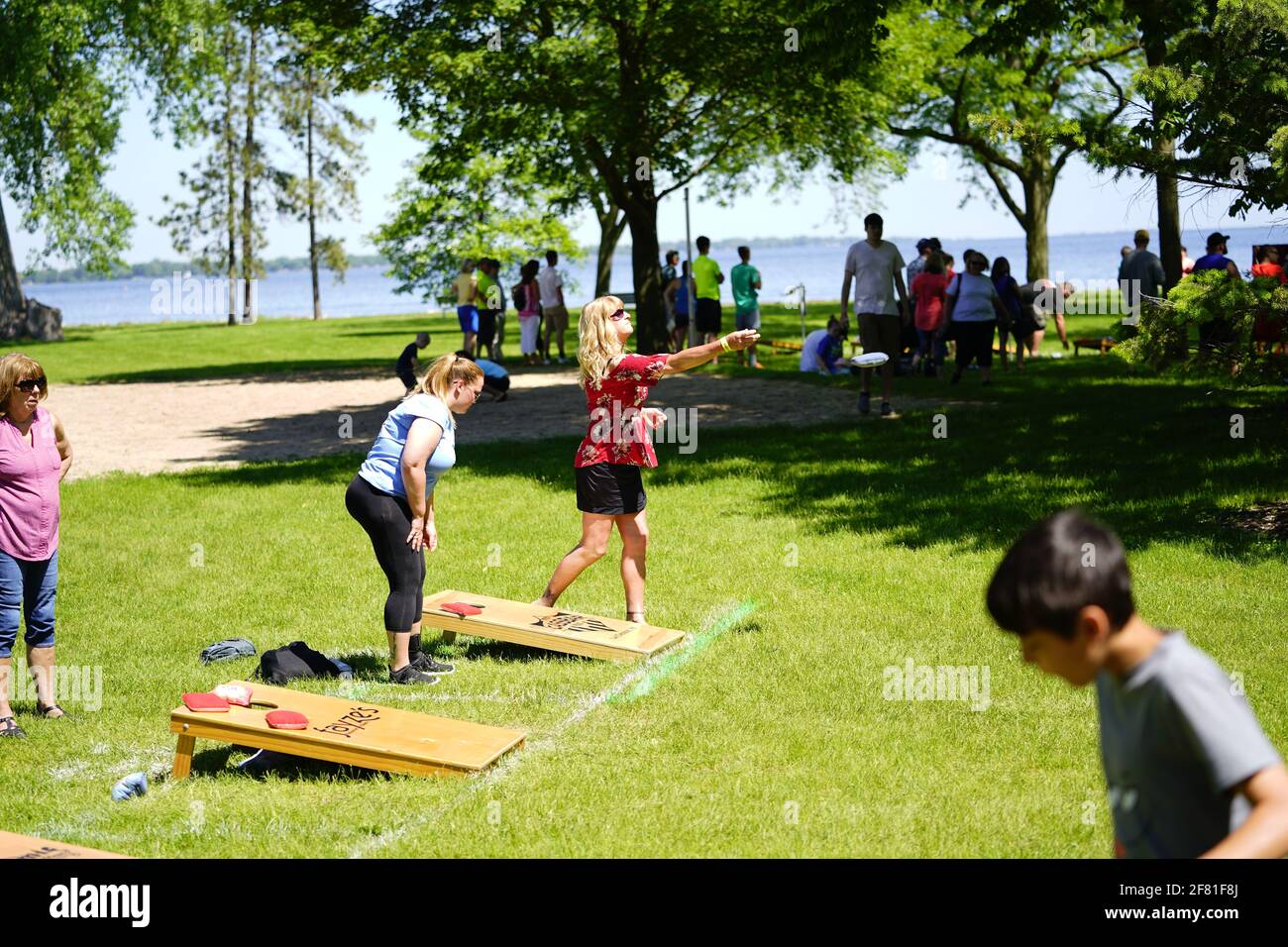 I maschi e le femmine giocano un gioco di lancio di sacco di fagioli all'evento del fine settimana di Walleye al parco del lago, come una comunità si riuniscono. Foto Stock