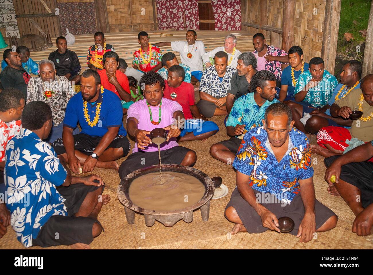 Seduti intorno alla ciotola di kava, le Fiji locali preparano a gustare questa bevanda tradizionale, in un piccolo villaggio insulare nelle Fiji. Foto Stock