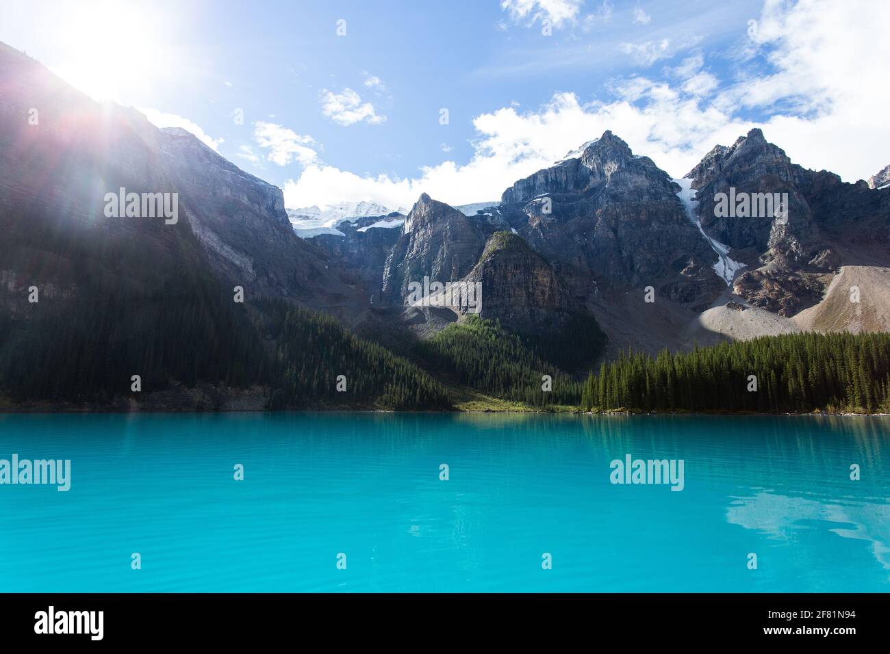 il sole si sveglia dietro una vista di montagna da un turchese luminoso lago Foto Stock