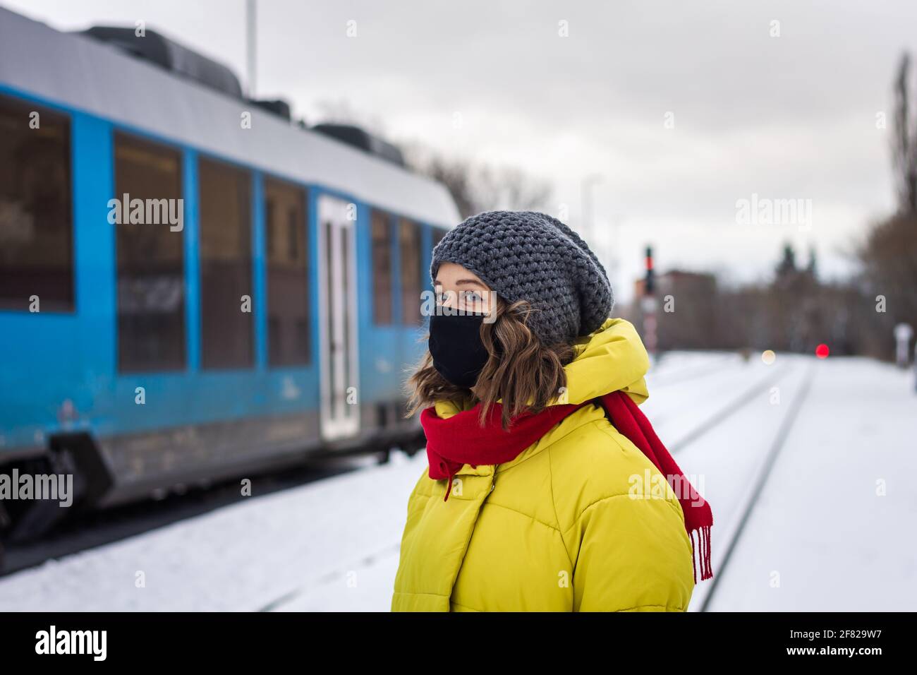 Trasporto durante la pandemia di coronavirus covid-19. Donna con maschera facciale viaggia in treno in inverno. Nuova normalità in città Foto Stock
