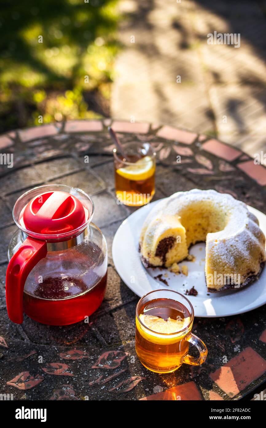 Picnic in primavera. Tè in tazza e teiera con torta in padella sul tavolo all'aperto. Serve dessert e bevande calde nel giardino di primavera Foto Stock