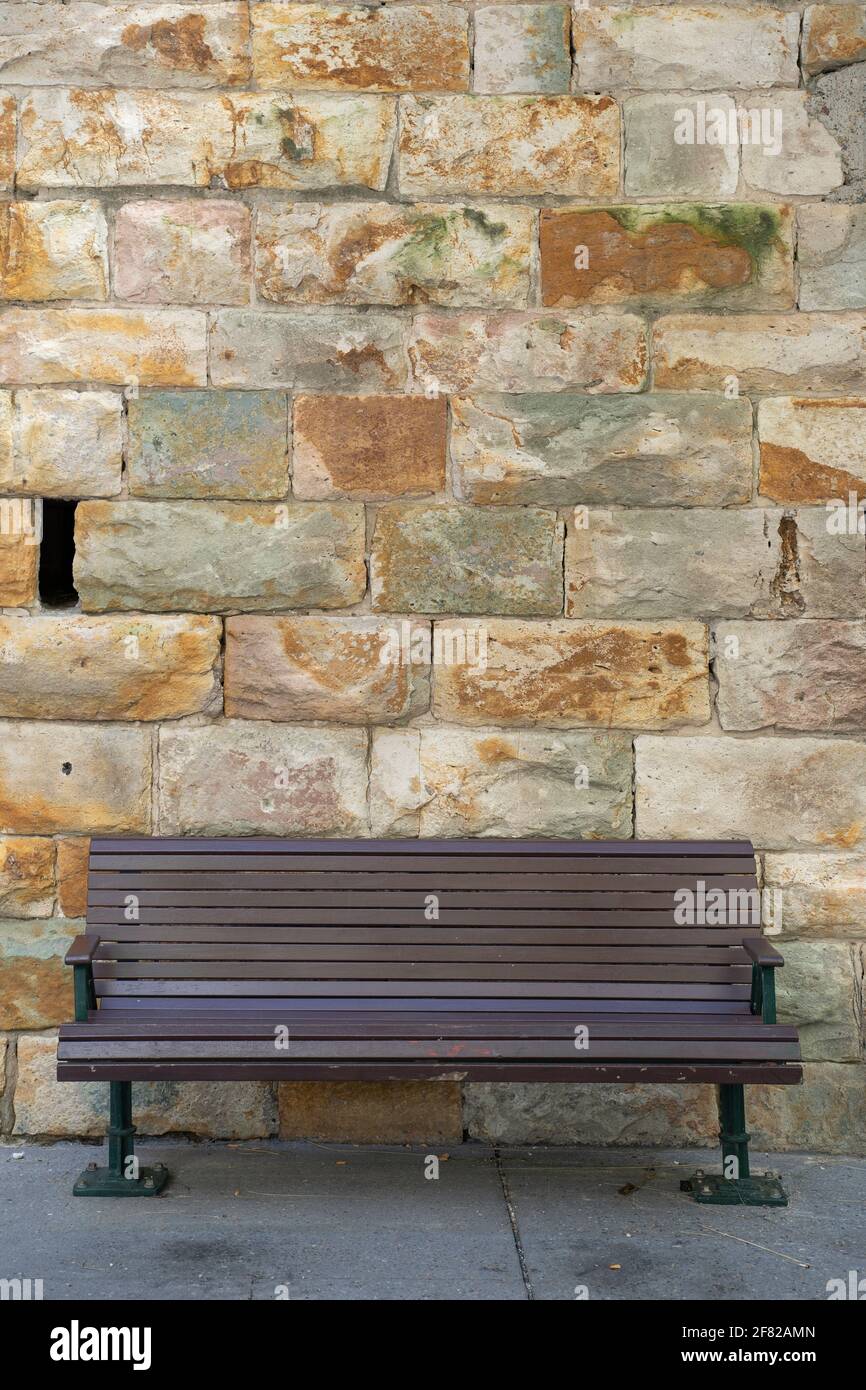 panca di legno di fronte ad un muro di arenaria Foto Stock