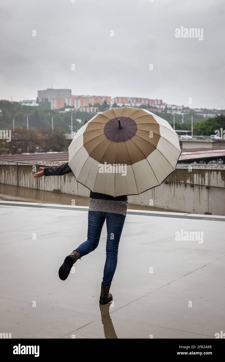 Donna con ombrello che si gode la pioggia in città. Felice quando piove.  Overcast sopra la strada in centro Foto stock - Alamy