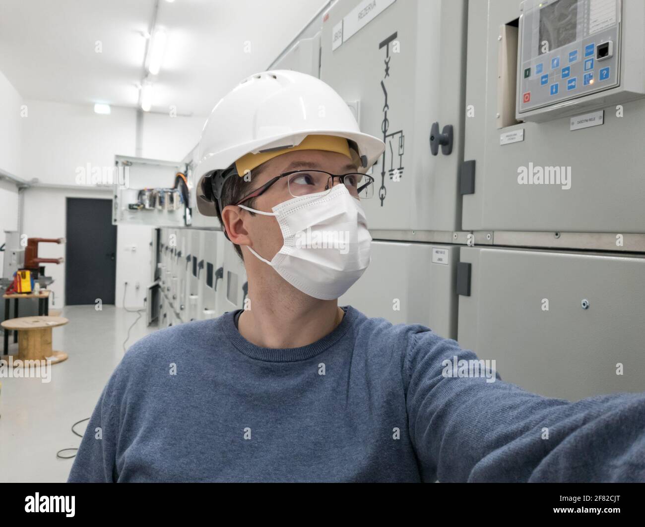 Giovane ingegnere che lavora in sottostazione elettrica indossando una maschera facciale. Foto Stock