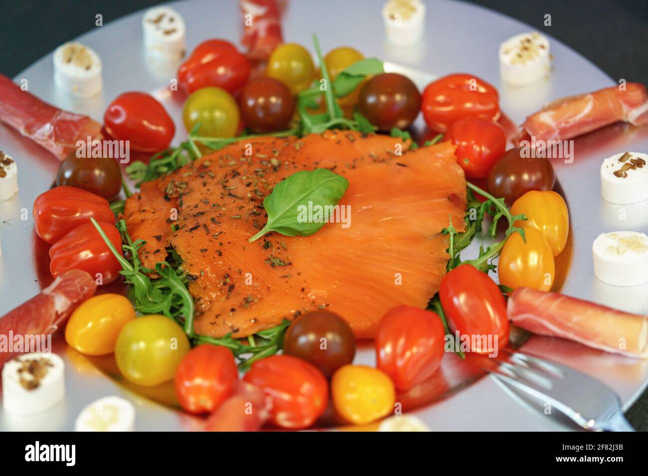 Un piatto di carne fredda con salmone fresco, pomodori e insalata di razzi disposti su un piatto d'argento Foto Stock