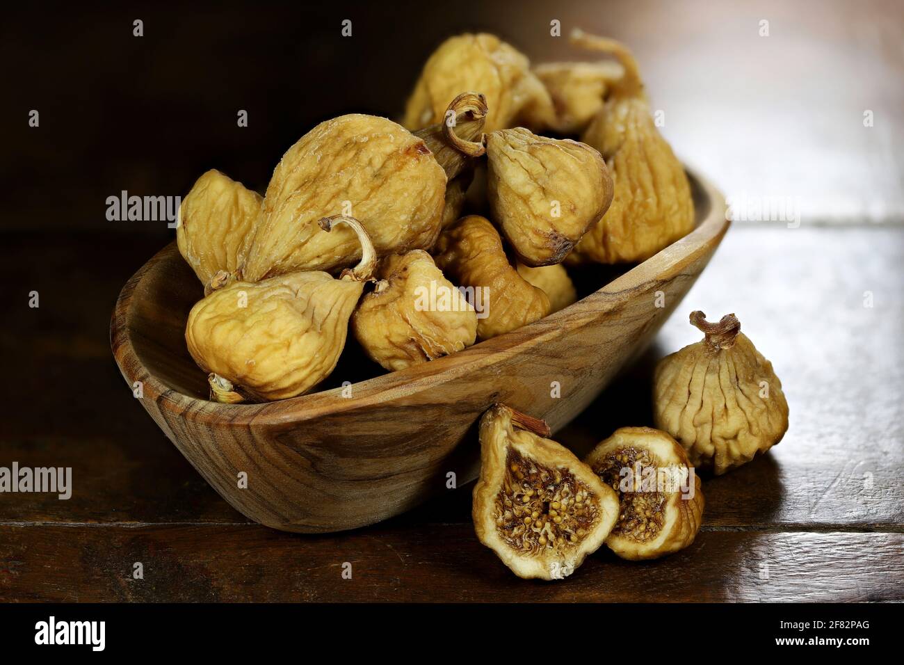 fichi selvatici secchi in una ciotola di ulivo isolato su rustico tavolo di legno Foto Stock