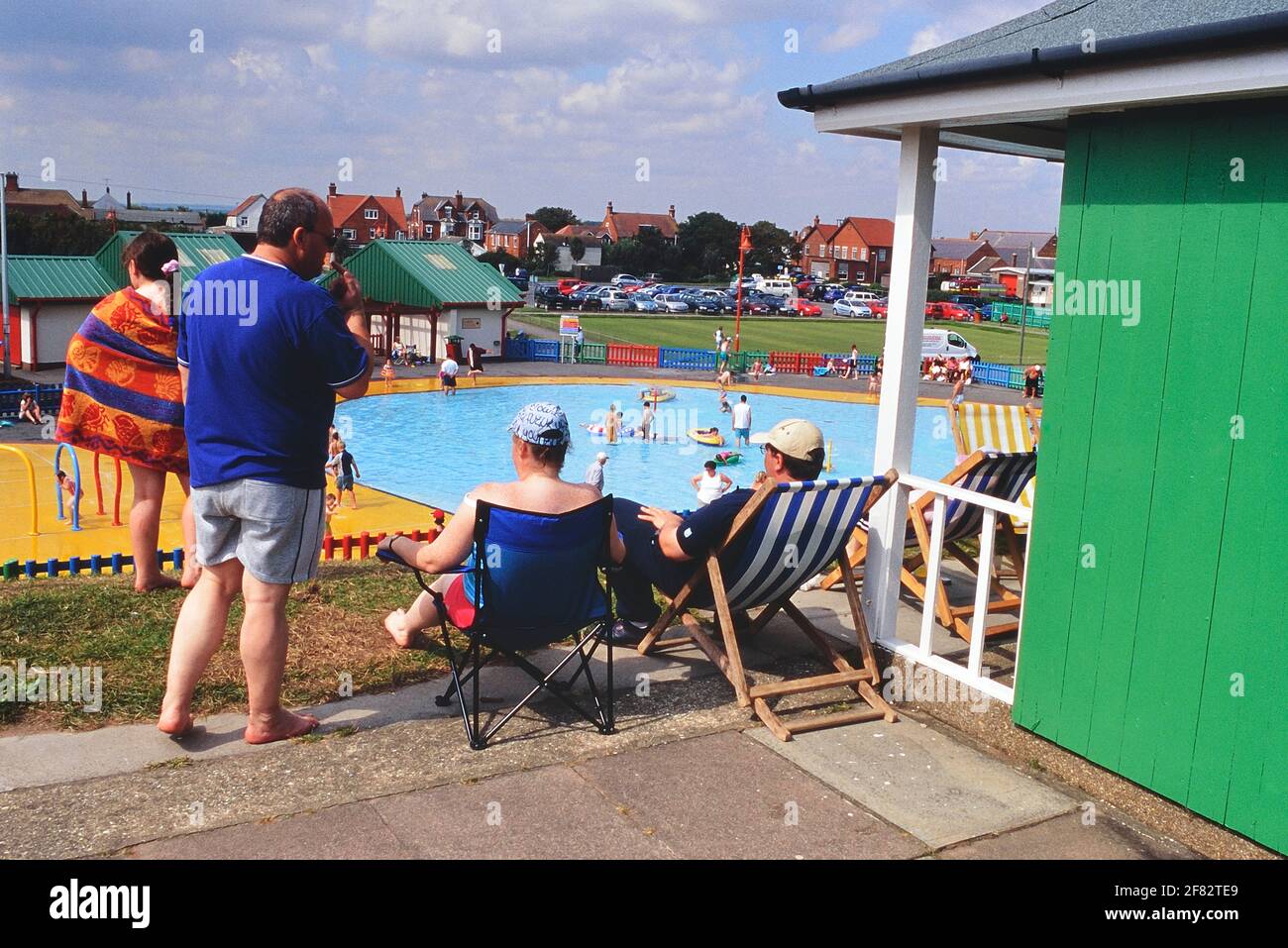 I vacanzieri presso il loro chalet sulla spiaggia vicino alla piscina con spruzzi del Queen's Park. Mablethorpe. Lincolnshire. Inghilterra, Regno Unito Foto Stock