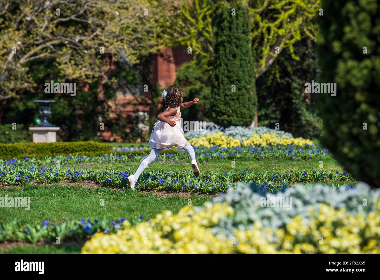 Una giovane afroamericana vestita nel suo meglio pasquale corre attraverso i giardini del Castello Smithsonian a Washington, D.C. Foto Stock