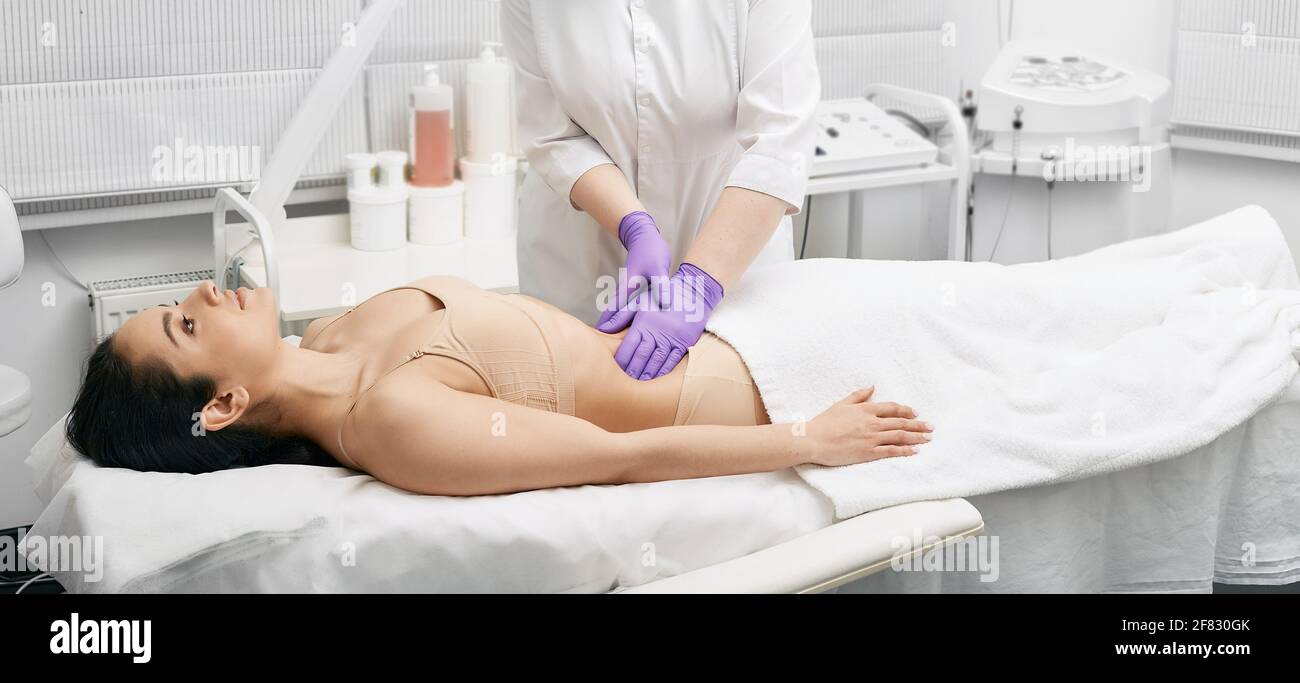 il medico palpa la pancia di una giovane donna in una clinica medica. Medico che fa un esame medico per il corpo femminile per la prevenzione delle malattie Foto Stock