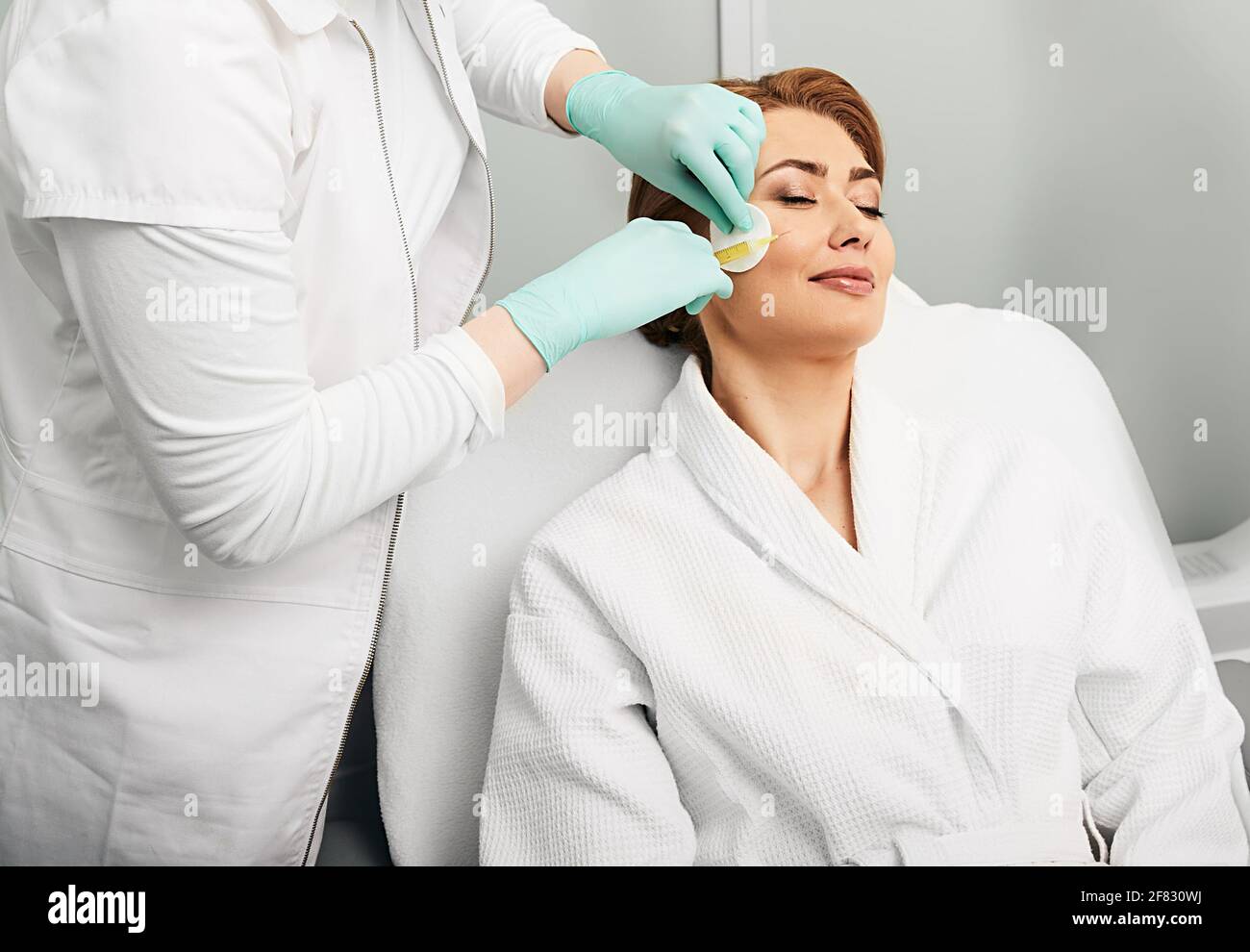 La donna con gli occhi chiusi riceve iniezioni anti-invecchiamento con plasma sanguigno. Plasmolifting, terapia PRP facciale Foto Stock