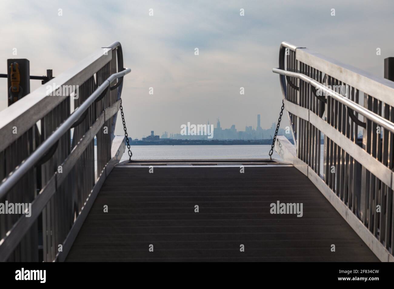 il ponte passeggeri del traghetto si è tirato verso l'alto con l'ombra di a. città sullo sfondo Foto Stock