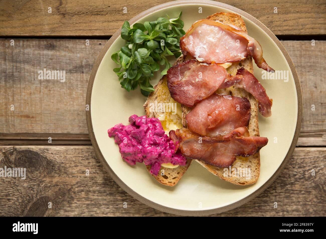 Rashers di pancetta affumicata posteriore che è stato grigliato e servito su pane tostato di pasta acida con lattuga agnelli e un condimento di rafano e barbabietola. T Foto Stock