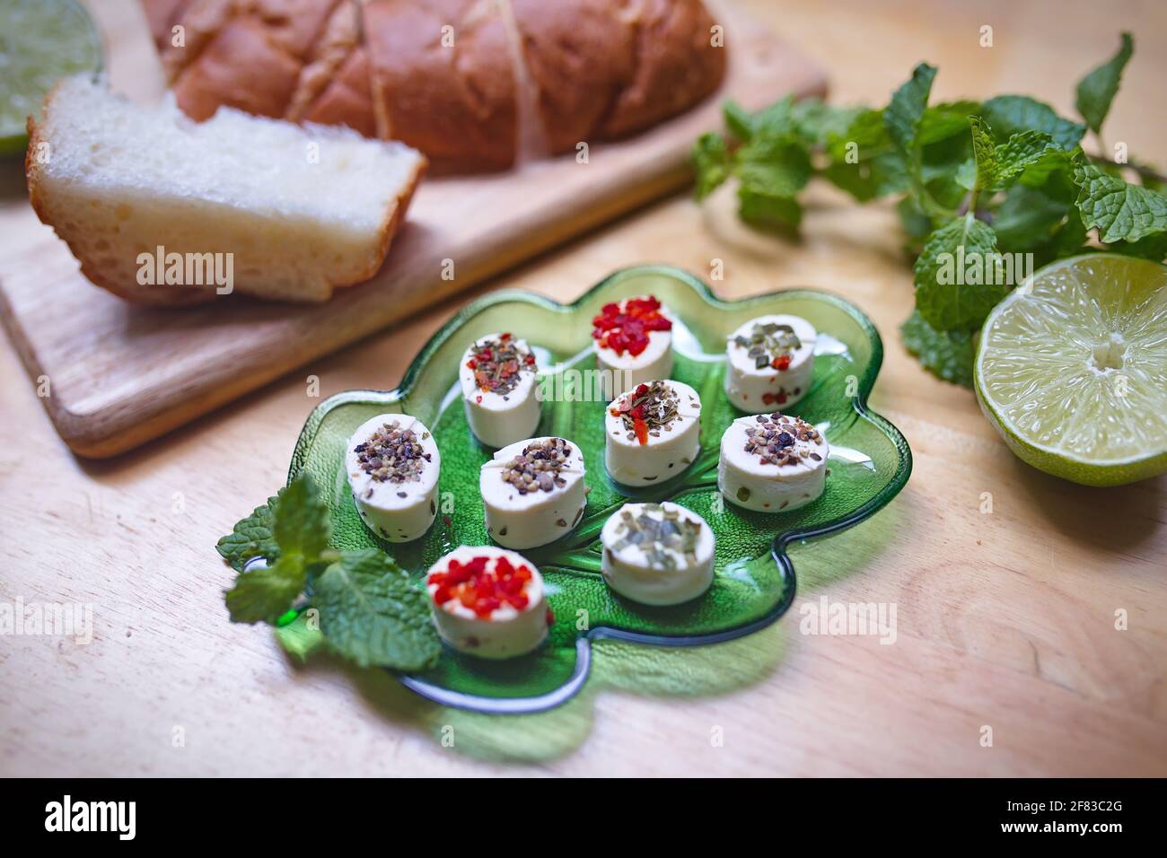 Pezzi di formaggio di capra su piatto di vetro verde Foto Stock