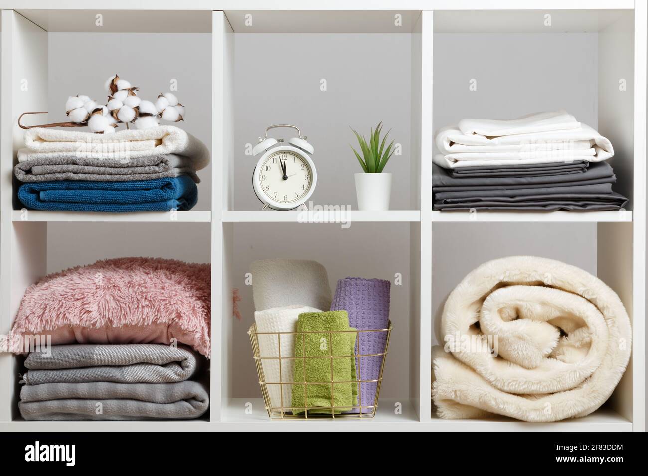 Organizzazione dello storage. Pile di asciugamani, lenzuola, lenzuola, coperte e cuscini su un ripiano bianco. Foto Stock