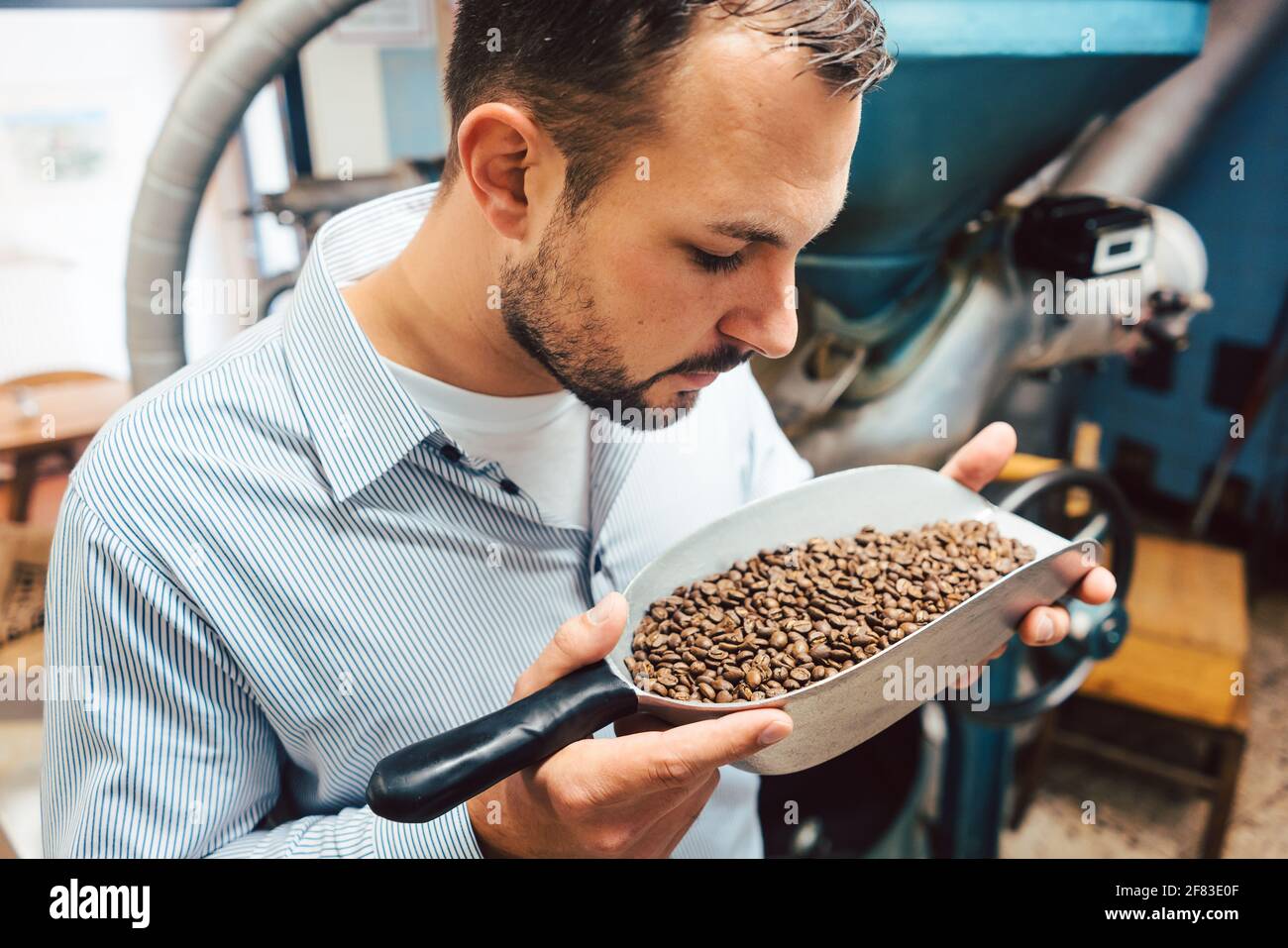 Uomo in coffee roastery con chicchi freschi Foto Stock