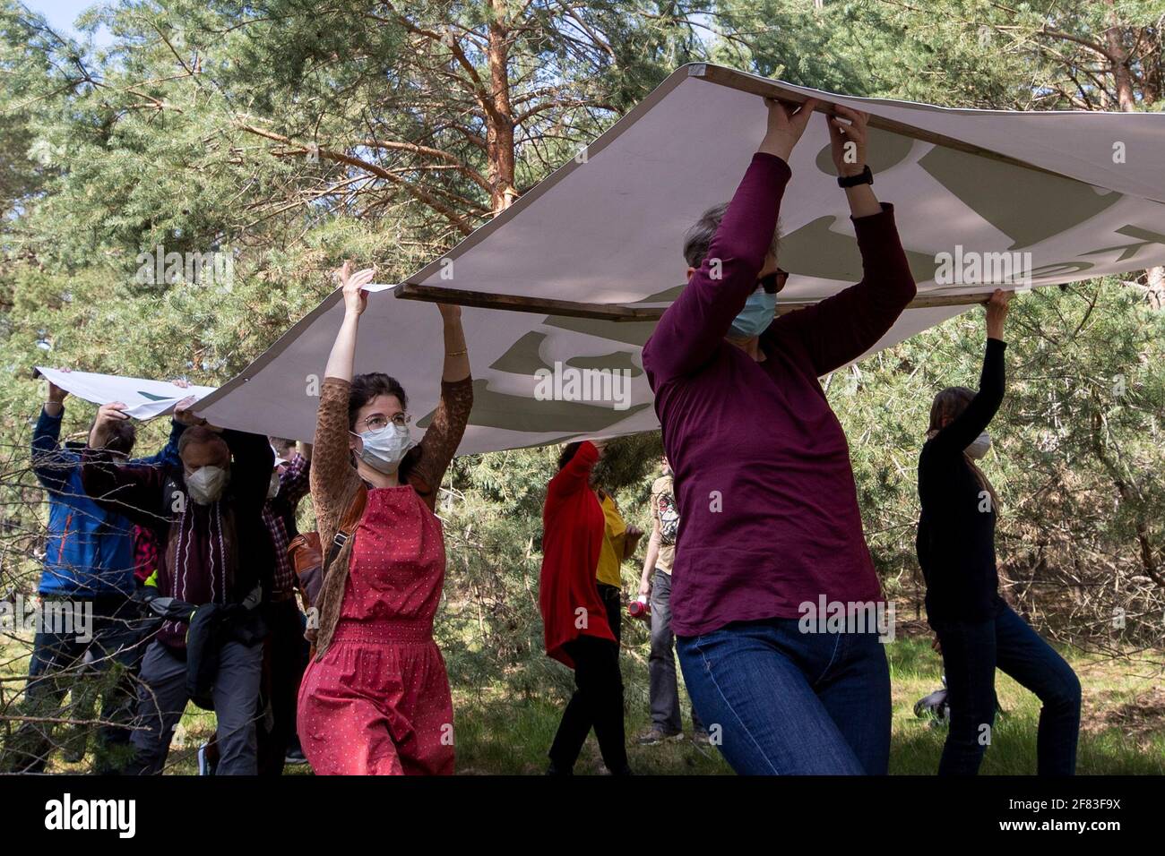 Schleife, Germania. 11 Apr 2021. Una bandiera con l'iscrizione 'UNVERKÄUFLICH www.kein-tagebau.de' è trasportato attraverso la foresta vicino a Schleife. L'azione di protesta 'Unverkäuflich' della rete ambientale Grüne Liga a Schleife, nei pressi della miniera d'opencast Nochten, nel distretto di Görlitz, è diretta contro il minacciato dragaggio di LEAG (Lausitz Energie Bergbau AG). Credit: Daniel Schäfer/dpa-Zentralbild/dpa/Alamy Live News Foto Stock