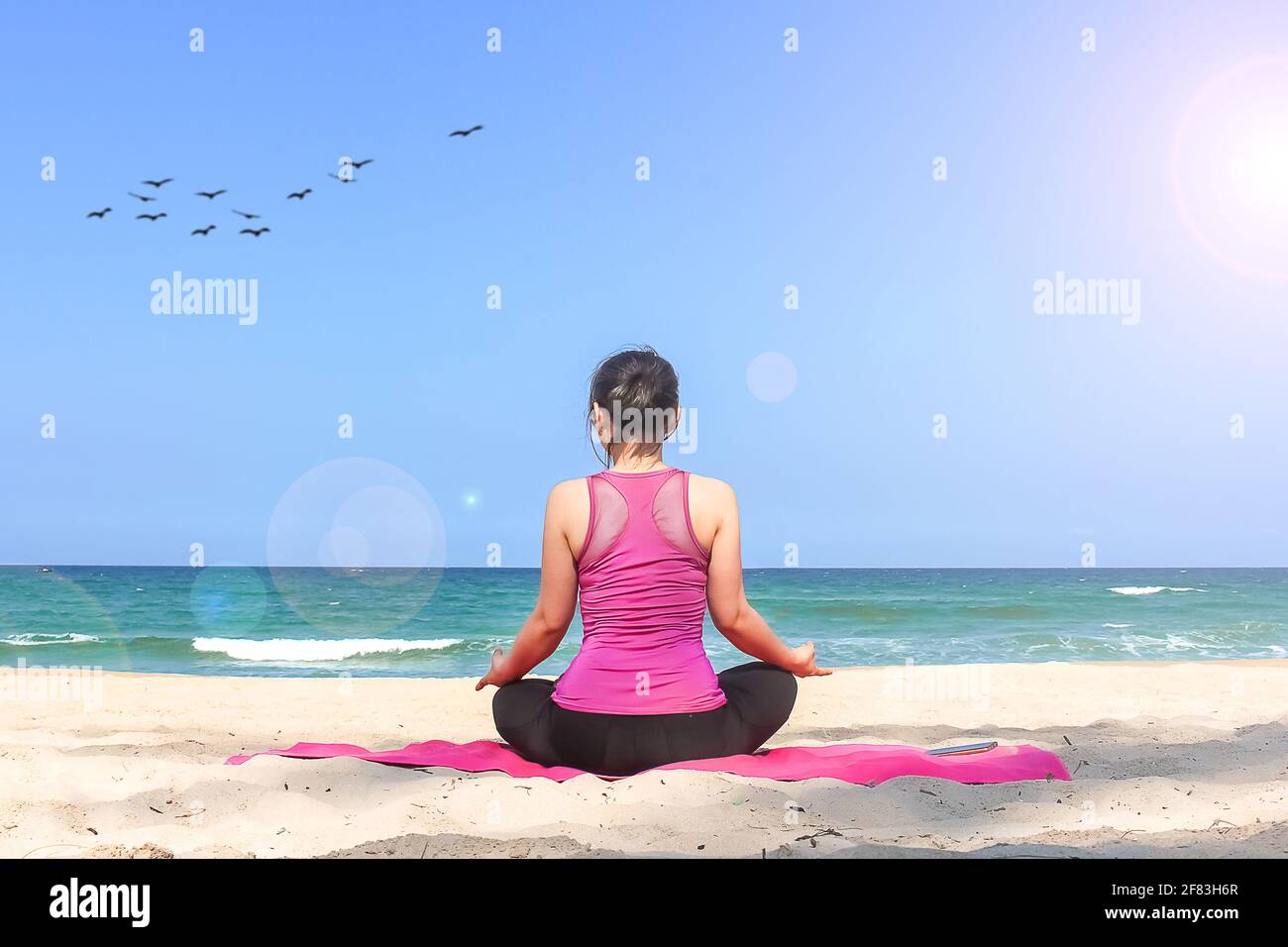 Giovane donna fare yoga sulla spiaggia in sole naturale luce del giorno Foto Stock