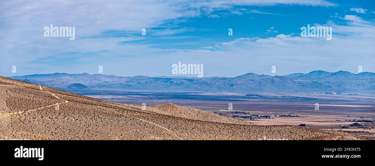 Colline del deserto marrone che si affaccia valle oltre sotto il cielo blu con nuvole bianche Foto Stock