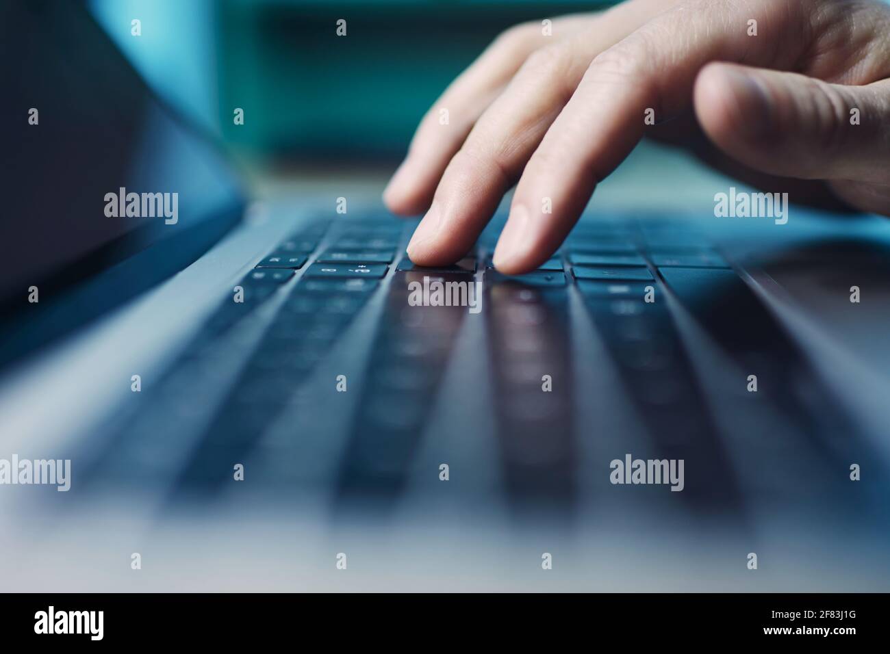 Selezione della messa a fuoco selettiva sulla tastiera del computer. Dita di persona durante l'uso del computer portatile di notte. Foto Stock