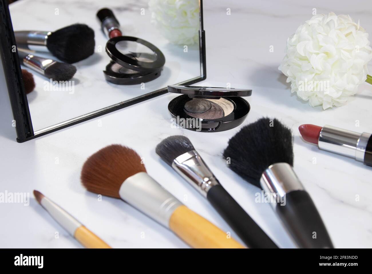Still Life of Make-up Pennelli, Lipstick, Specchio e tessuto Fiore sullo sfondo Foto Stock