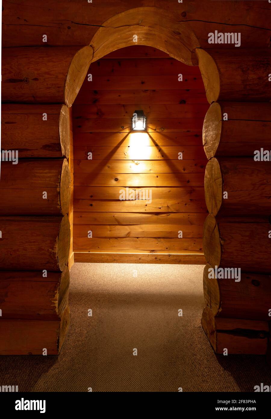 vista di un passaggio arcuato in legno e di una parete montata luce sullo sfondo Foto Stock