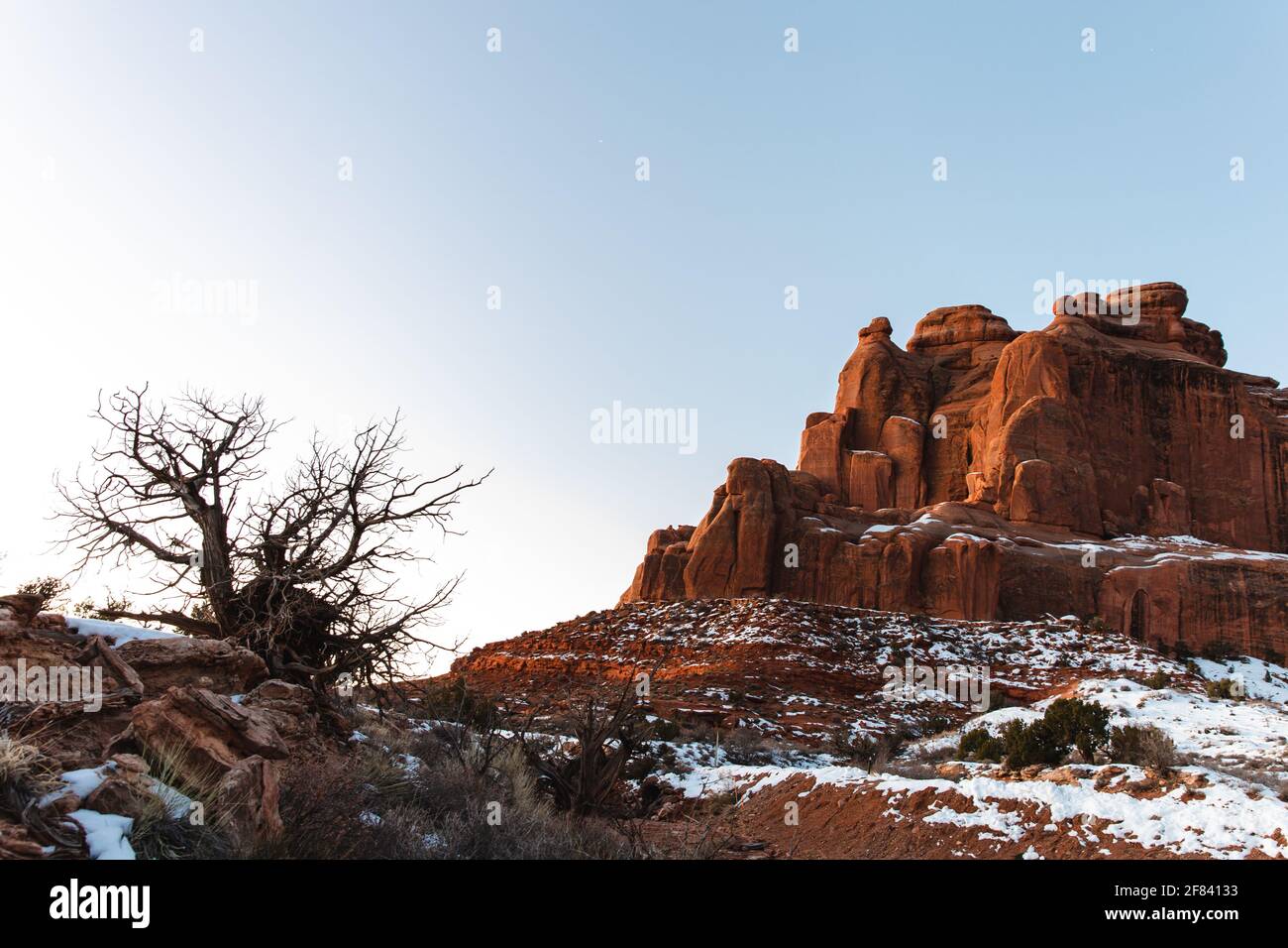 scogliera di roccia rossa con il sole che sorge in inverno con neve a terra Foto Stock