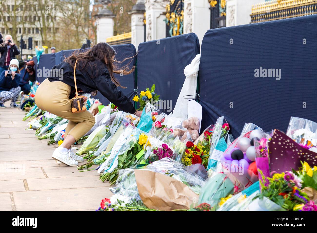 11 aprile 2021, Londra, Regno Unito - persone che posano fiori come tributo al principe Filippo, duca di Edimburgo fuori da Buckingham Palace dopo la sua morte il 9 aprile Foto Stock